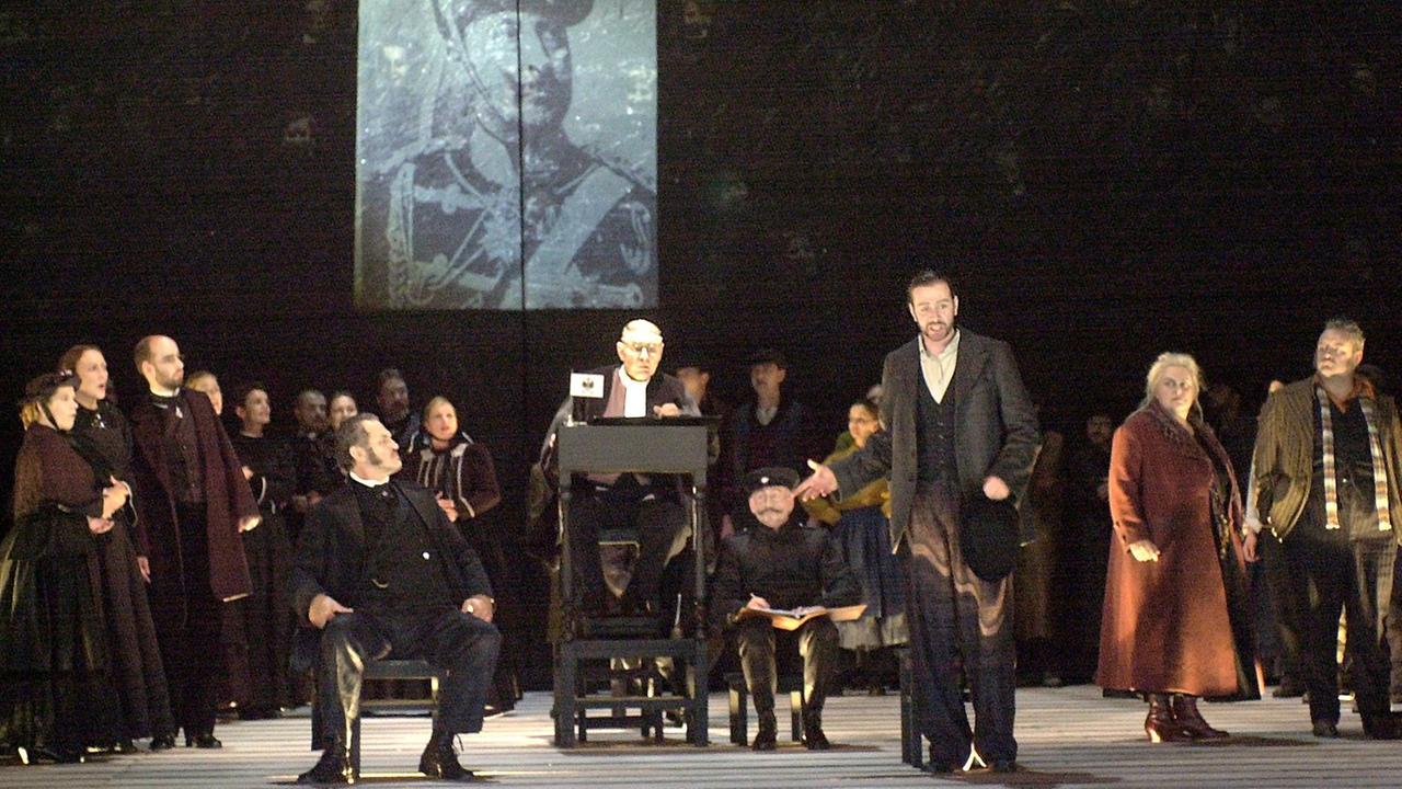 In einer Szene der Oper "Levins Mühle" klagt Leo Levin (Tom Erik Lie, 3.v.r.) den deutschen Mühlenbesitzer Johann (Florian Cerny, sitzend Mitte l.) vor dem Richter (Andreas David, M.) an, seine Mühle zerstört zu haben. In einer Szene der Oper "Levins Mühle" klagt Leo Levin (Tom Erik Lie, 3.v.r.) den deutschen Mühlenbesitzer Johann (Florian Cerny, sitzend Mitte l.) vor dem Richter (Andreas David, M.) an, seine Mühle zerstört zu haben.