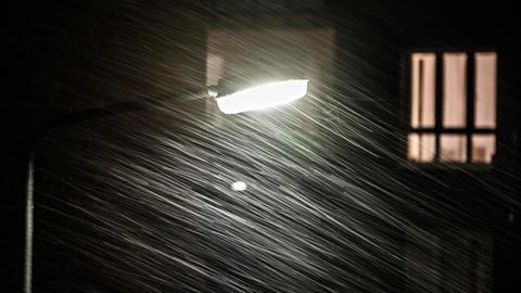 Das Licht einer Laterne fällt in einer stürmischen Nacht auf strömenden Regen.