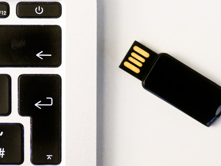 Großaufnahme eines USB-Sticks neben einer Laptop-Tastatur. Von der Tastatur sind nur sechs Tasten zu sehen, u.a. die Eingabe- und die Zurücktaste. Großaufnahme eines USB-Sticks neben einer Laptop-Tastatur. Von der Tastatur sind nur sechs Tasten zu sehen, u.a. die Eingabe- und die Zurücktaste.