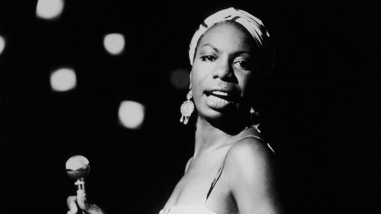 Nina Simone schaut zu Seite genau in die Kamera bei einem Konzert 1964.