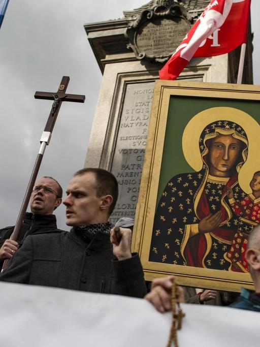 Gläubige auf dem Warschauer Rosenkranz-Marsch tragen Kruzifixe, Marienbildnisse und polnische Nationalflaggen.