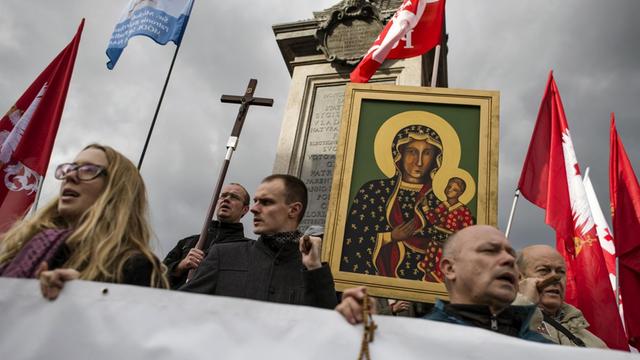 Gläubige auf dem Warschauer Rosenkranz-Marsch tragen Kruzifixe, Marienbildnisse und polnische Nationalflaggen.