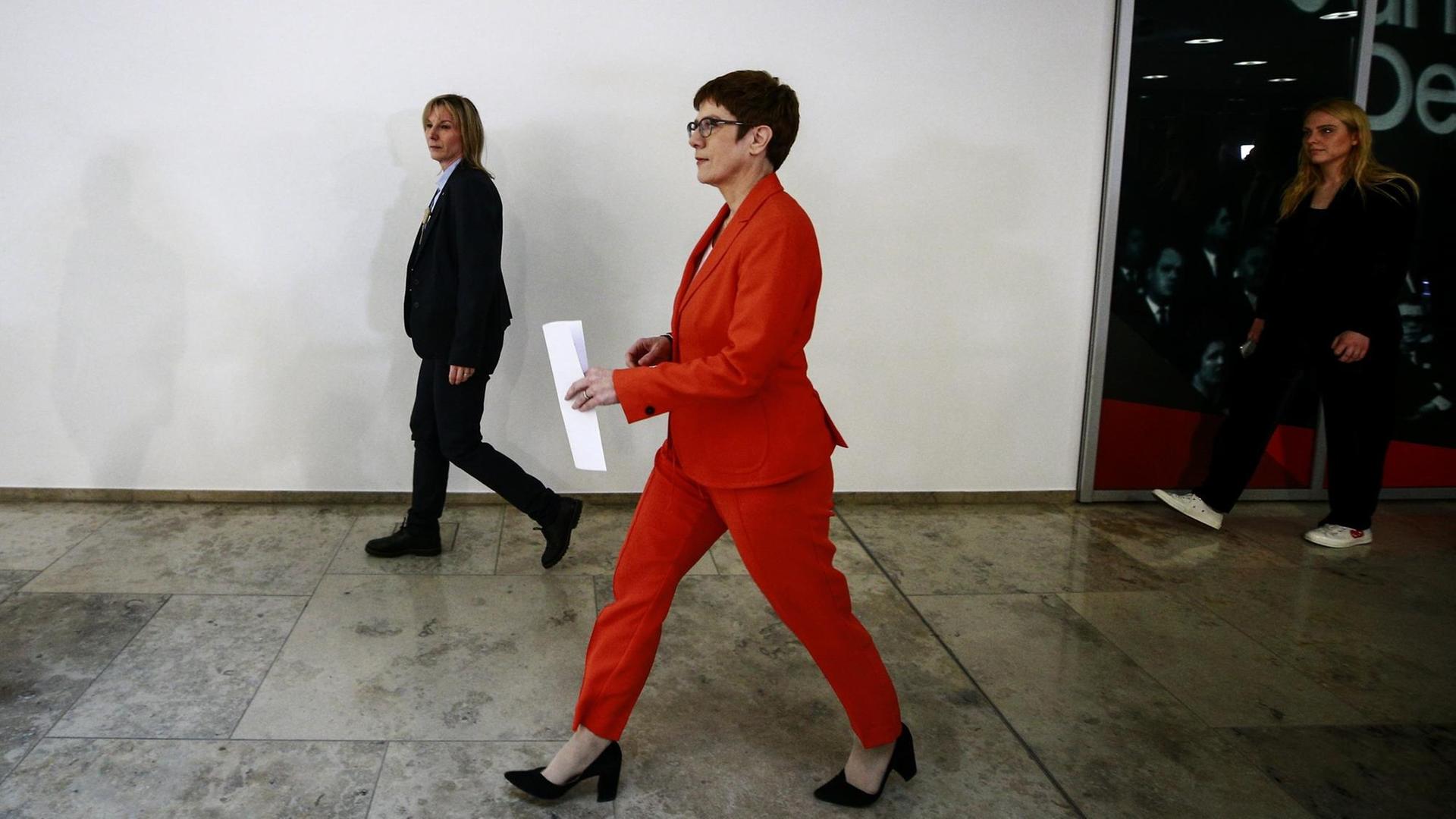 CDU-Chefin und Verteidigungsministerin Annegret Kramp-Karrenbauer läuft in einem Gebäude einen Flur entlang. Sie trägt einen roten Hosenanzug. CDU-Chefin und Verteidigungsministerin Annegret Kramp-Karrenbauer läuft in einem Gebäude einen Flur entlang. Sie trägt einen roten Hosenanzug.