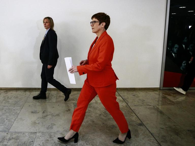 CDU-Chefin und Verteidigungsministerin Annegret Kramp-Karrenbauer läuft in einem Gebäude einen Flur entlang. Sie trägt einen roten Hosenanzug.
