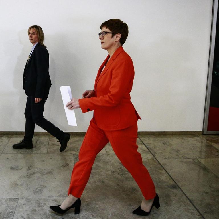 CDU-Chefin und Verteidigungsministerin Annegret Kramp-Karrenbauer läuft in einem Gebäude einen Flur entlang. Sie trägt einen roten Hosenanzug.