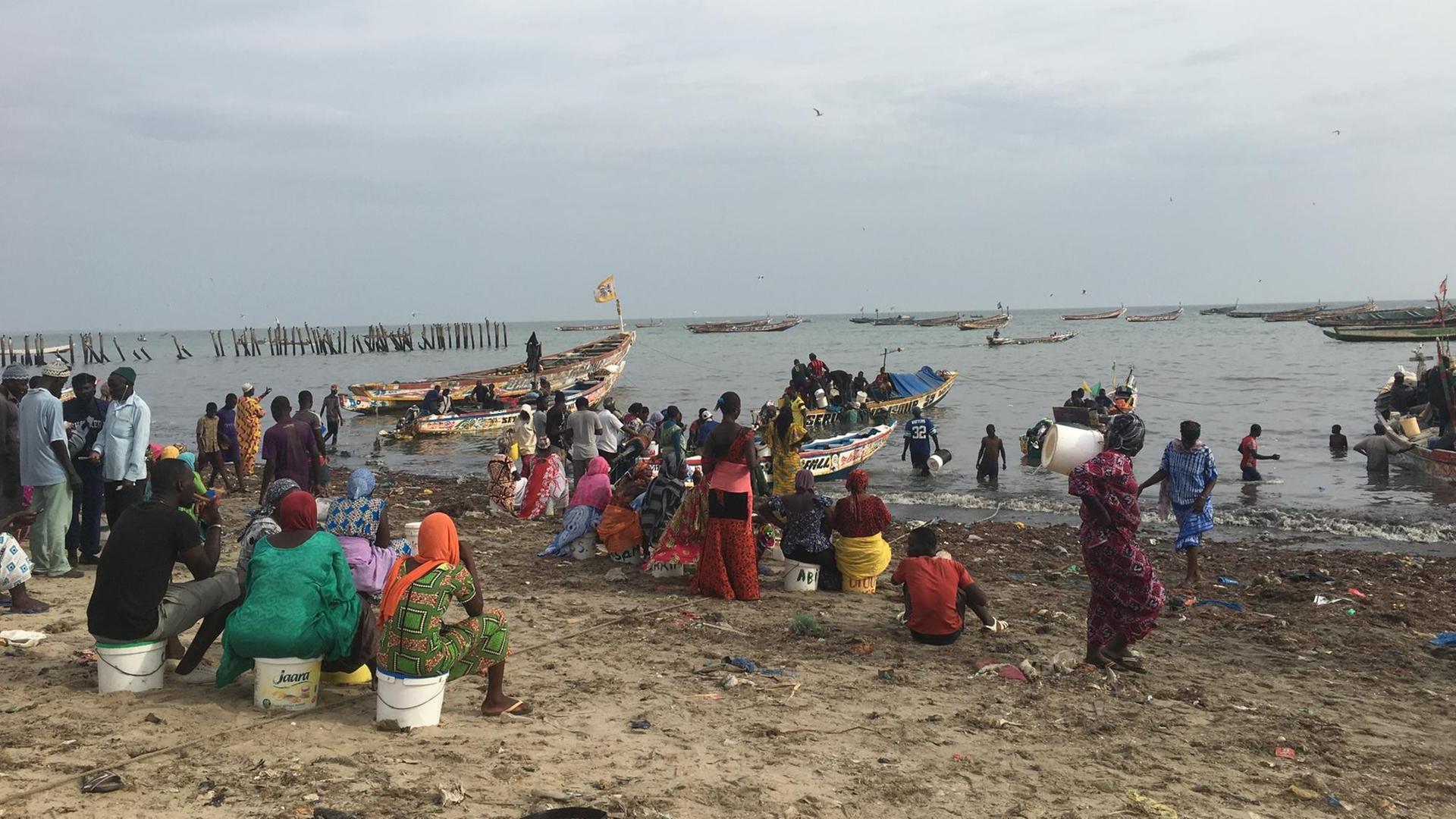 Am Strand von Mbour sitzen die Dofbewohner und warten auf die Rückkehr der Fischer.