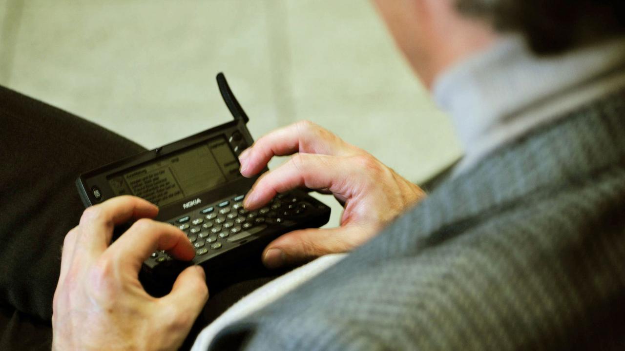 Ein Mann tippt auf dem Nokia 9110 Communicator. Ein Mann tippt auf dem Nokia 9110 Communicator.