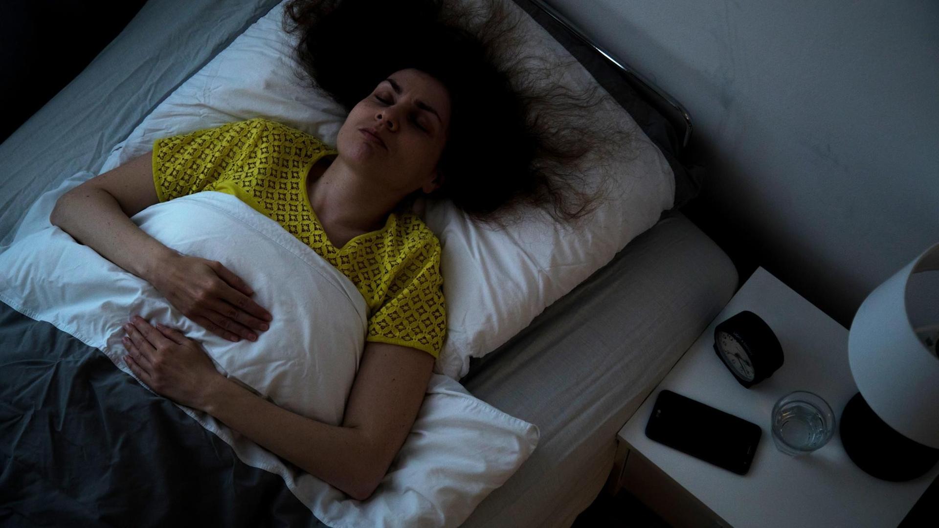 Eine Frau liegt in einem Bett und schläft Eine Frau liegt in einem Bett und schläft