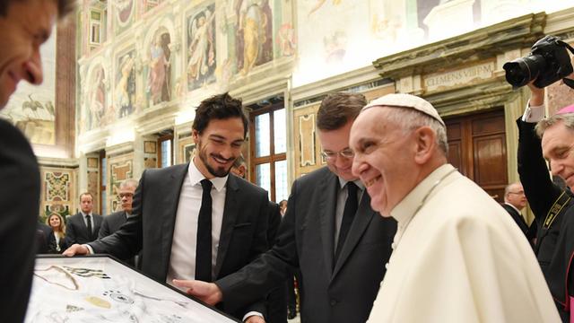 Die Nationalspieler Thomas Müller und Mats Hummels sowie DFB-Präsident Reinhard Grindel überreichen dem Papst ein Trikot.