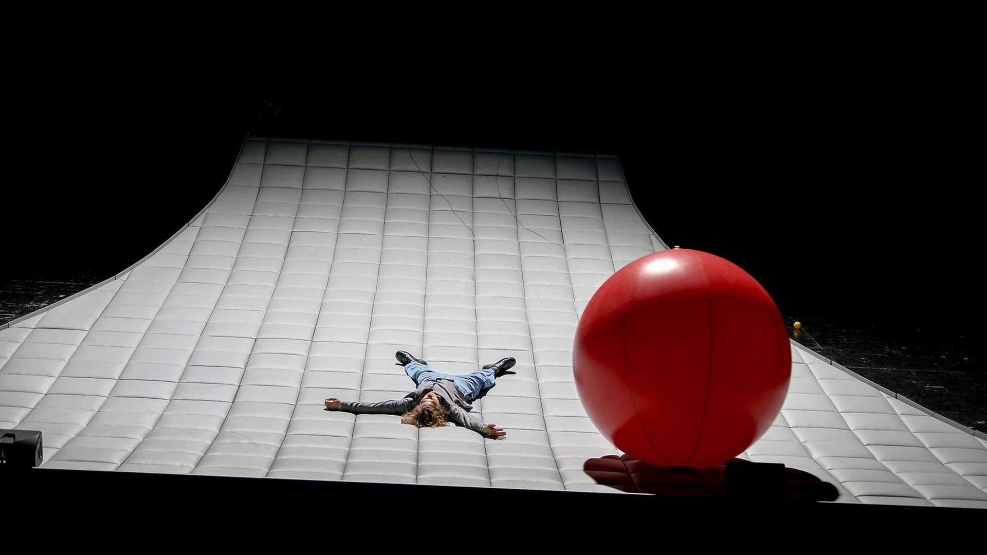 Der Schauspieler Moritz Kienemann liegt ausgestreckt auf einer riesigen Matratze, rechts neben ihm ein großer, roter Ball.