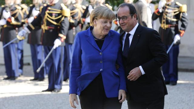 Bundeskanzlerin Angela Merkel (CDU) wird von Frankreichs Präsident Francois Hollande vor dem Elysée Palast in Paris begrüßt.