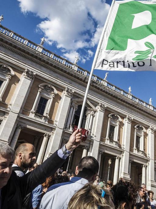Demonstranten schwenken vor einem klassischen Gebäude in Rom eine Flagge