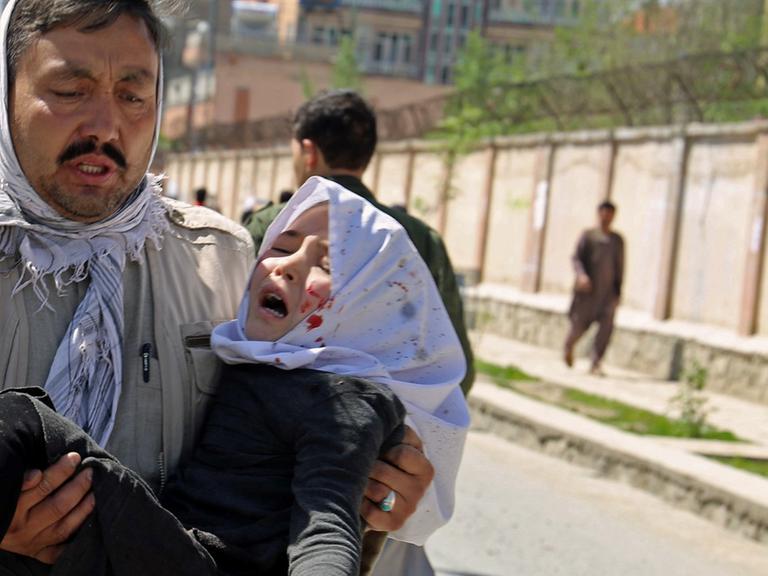 Ein Mann trägt am 22.4.2018 in der afghanischen Hauptstadt Kabul ein bei einem Selbstmordanschlag verwundetes Kind.