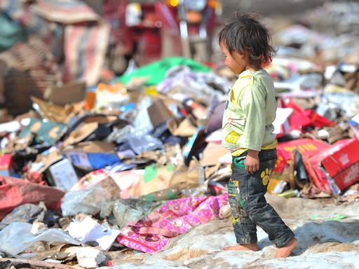 Ein kleiner Junge läuft über eine Müllkippe