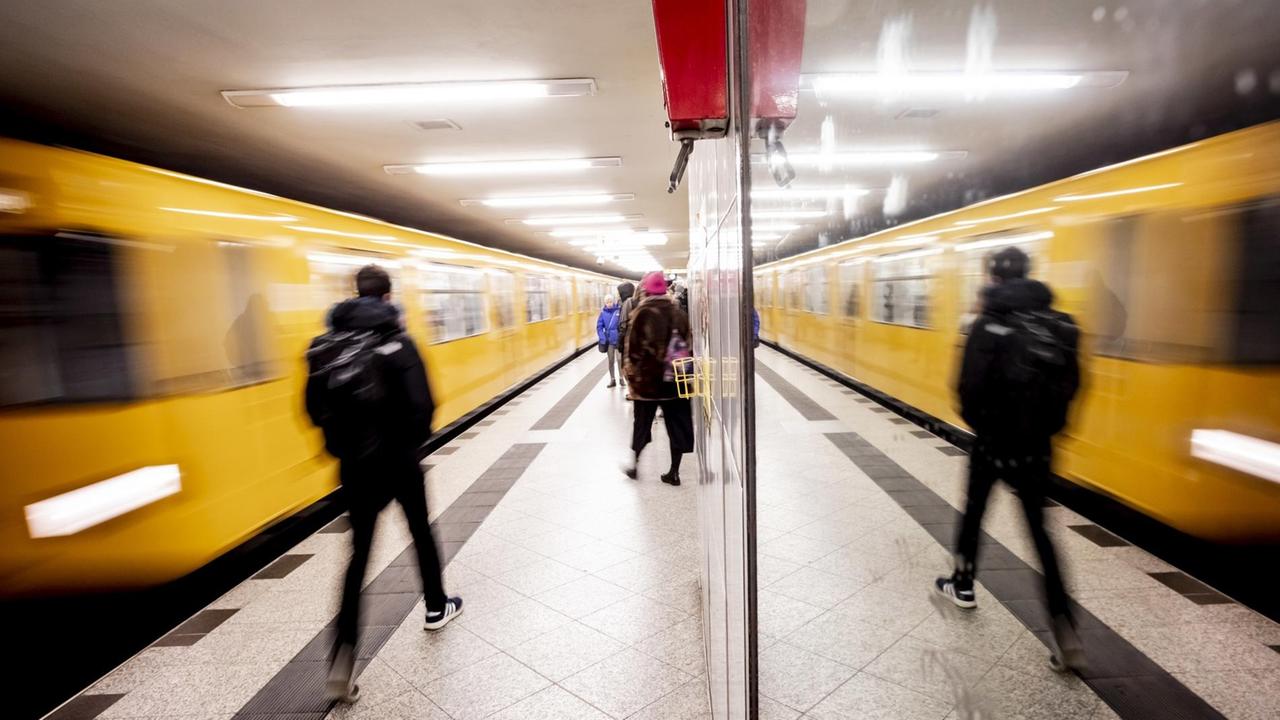 Eine U-Bahn fährt in den U-Bahnhof ein, die Szenerie spiegelt sich in einer Glasscheibe. Eine U-Bahn fährt in den U-Bahnhof ein, die Szenerie spiegelt sich in einer Glasscheibe.