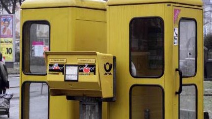 Alte gelbe Telefonzellen stehen hinter einem Briefkasten in Frankfurt/Main