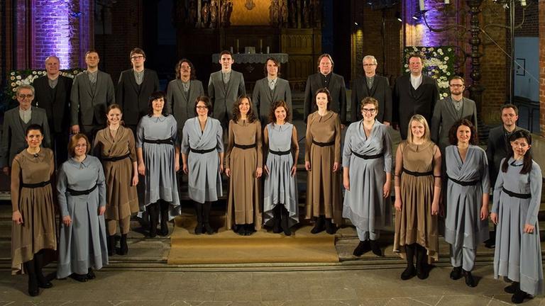 Der Chor steht im Halbkreis in einer bunt beleuchteten Kirche. Der Chor steht im Halbkreis in einer bunt beleuchteten Kirche.