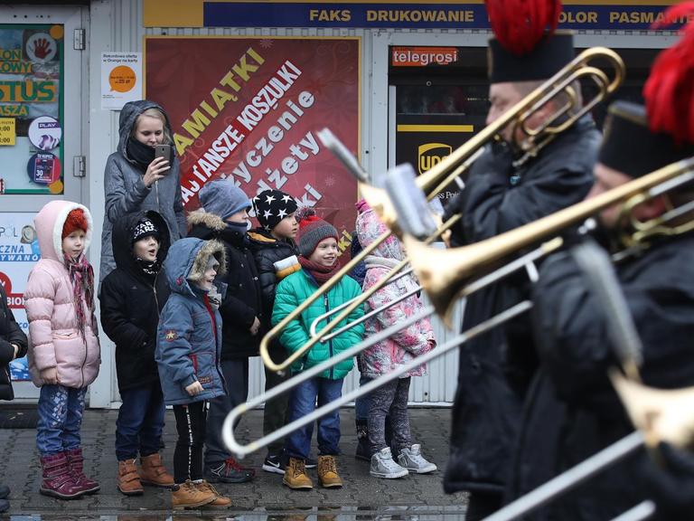 Eine polnische Blaskapelle geht an einer Gruppe Kinder während eines Marsches zu Ehren von Sankt Barbara vorbei.
