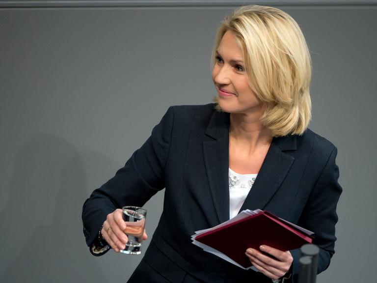 Zwei Männer und eine Frau im Business-Look beugen sich über ein Laptop.