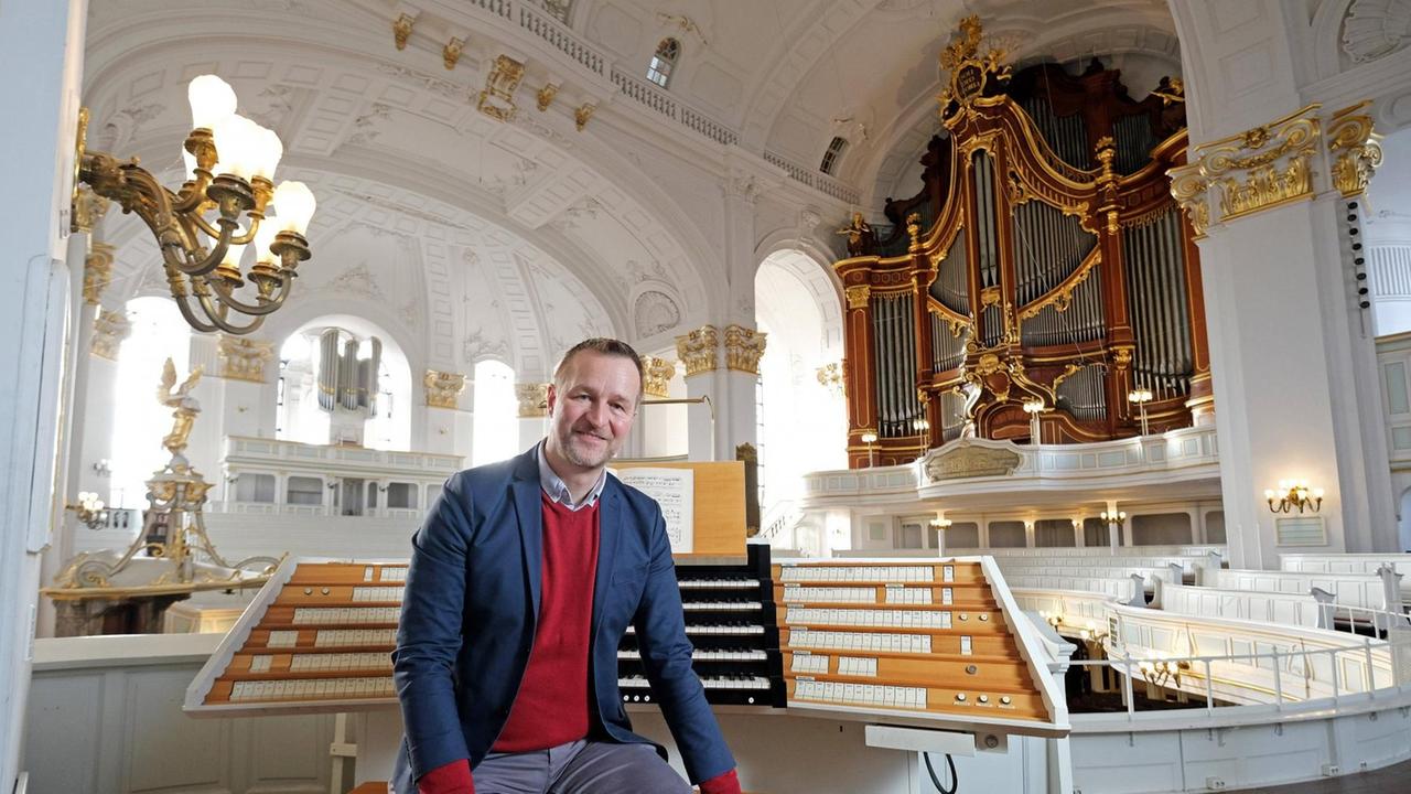Der Organist sitzt locker auf der Orgelbank, hinter der die Manuale und die Orgelpfeifen zu sehen sind. Der Organist sitzt locker auf der Orgelbank, hinter der die Manuale und die Orgelpfeifen zu sehen sind.