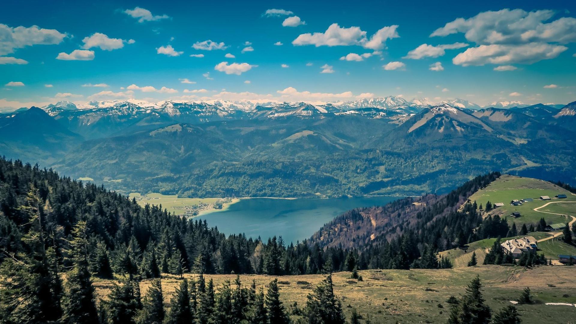 Der Blick fällt auf einen See, dessen blaue Tiefen von einer Bergkette umgeben sind. Der Blick fällt auf einen See, dessen blaue Tiefen von einer Bergkette umgeben sind.