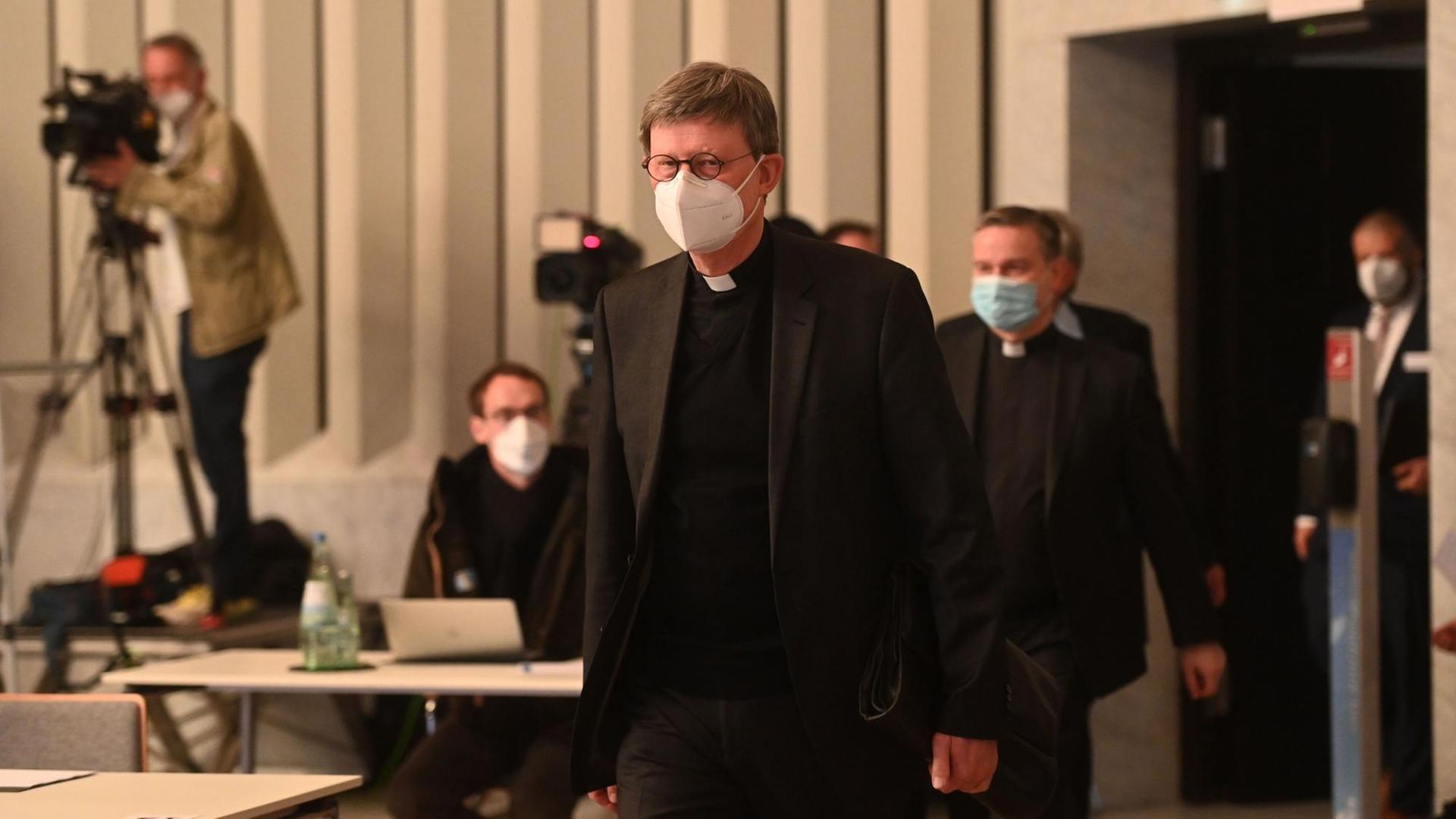 Kardinal Woelki kommt zur Presse-Konferenz. Im Hinter-Grund sind Kameras. Kardinal Woelki kommt zur Presse-Konferenz. Im Hinter-Grund sind Kameras.