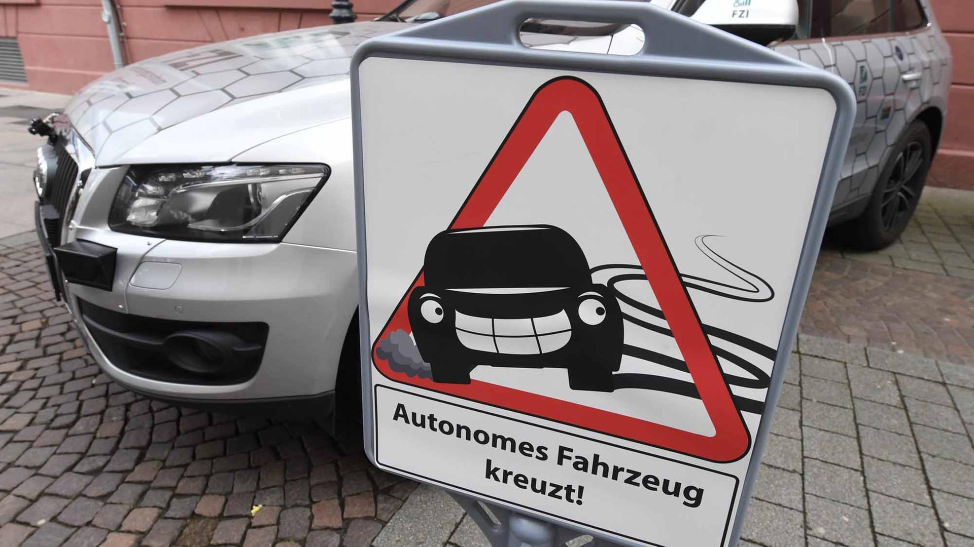 Vor dem Forschungsfahrzeug _Cocar_ für autonomes Fahren des Forschungszentrum Informatik (FZI) in Karlsruhe (Baden-Württemberg) steht am 28.04.2016 ein Schild, auf dem _Autonomes Fahrzeug kreuzt" zu lesen ist. Vor dem Forschungsfahrzeug _Cocar_ für autonomes Fahren des Forschungszentrum Informatik (FZI) in Karlsruhe (Baden-Württemberg) steht am 28.04.2016 ein Schild, auf dem _Autonomes Fahrzeug kreuzt" zu lesen ist.
