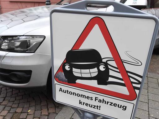 Vor dem Forschungsfahrzeug _Cocar_ für autonomes Fahren des Forschungszentrum Informatik (FZI) in Karlsruhe (Baden-Württemberg) steht am 28.04.2016 ein Schild, auf dem _Autonomes Fahrzeug kreuzt" zu lesen ist.