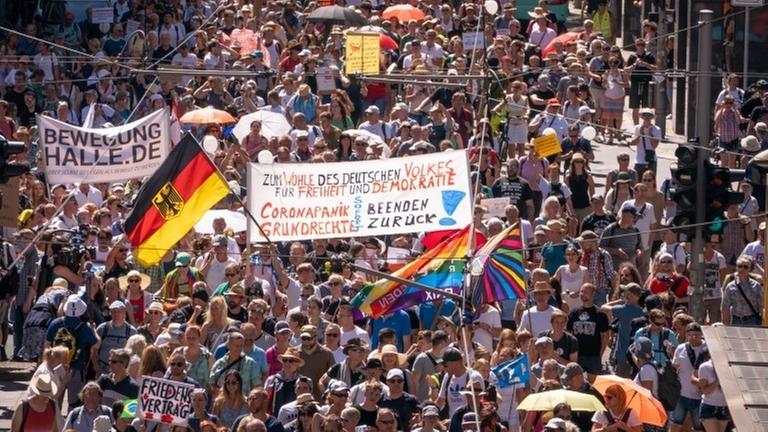 Viele Menschen laufen mit Schildern und Fahnen über eine Straße. Viele Menschen laufen mit Schildern und Fahnen über eine Straße.