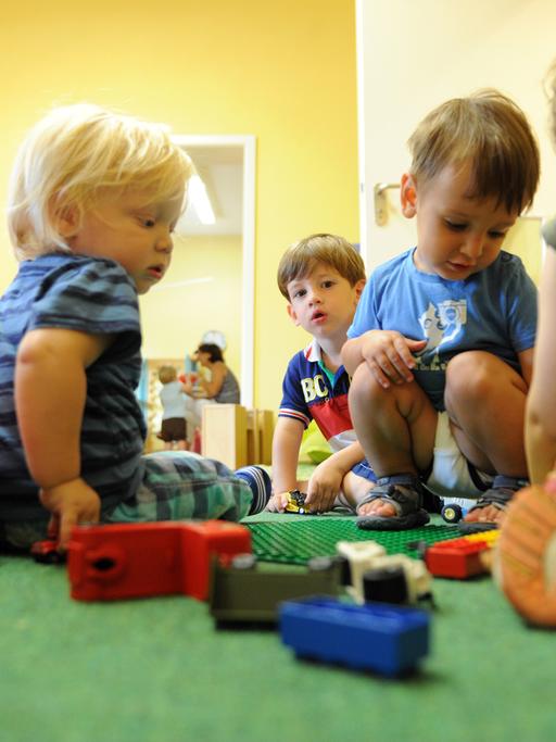 Kinder sitzen am Boden und spielen mit Spielzeug