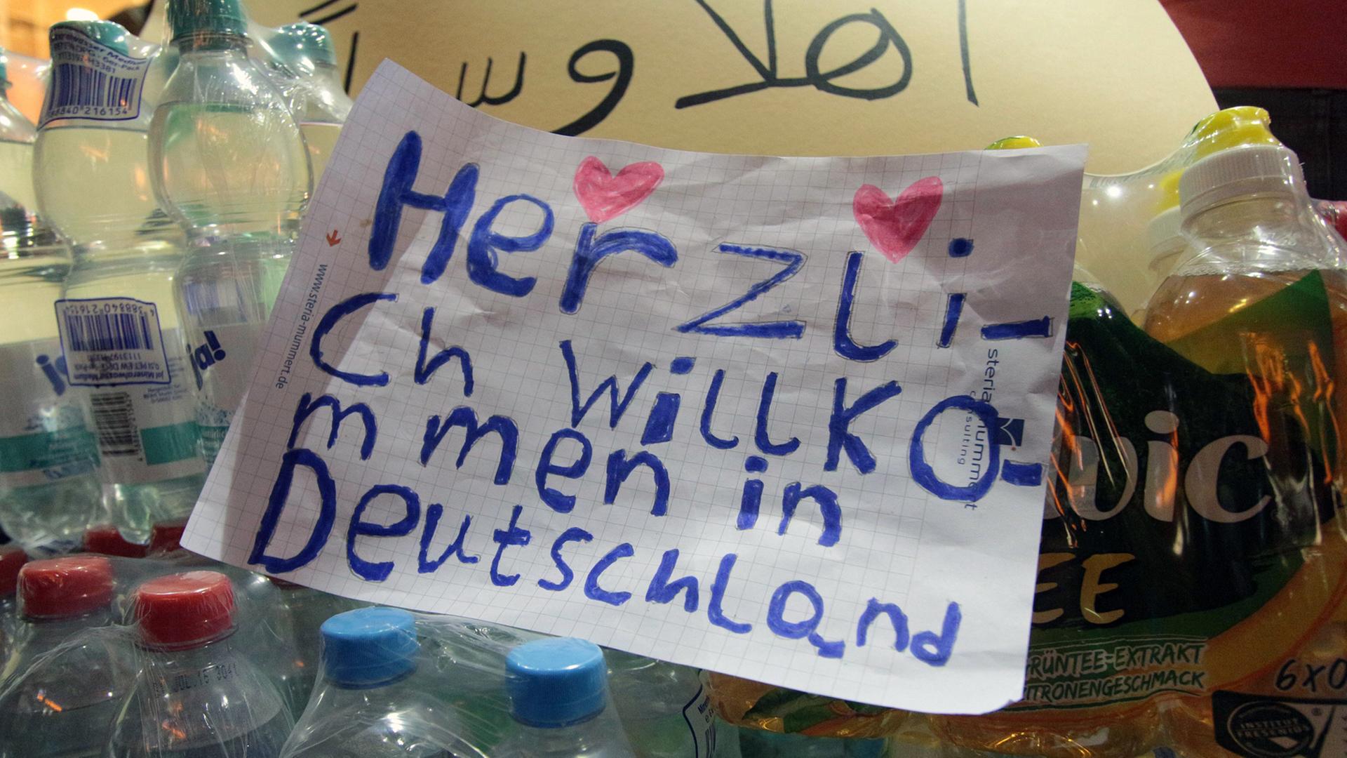 "Herzlich Willkommen in Deutschland" steht mit zwei Herzchen in Kinderschrift auf einem Zettel zwischen Wasserflaschen "Herzlich Willkommen in Deutschland" steht mit zwei Herzchen in Kinderschrift auf einem Zettel zwischen Wasserflaschen