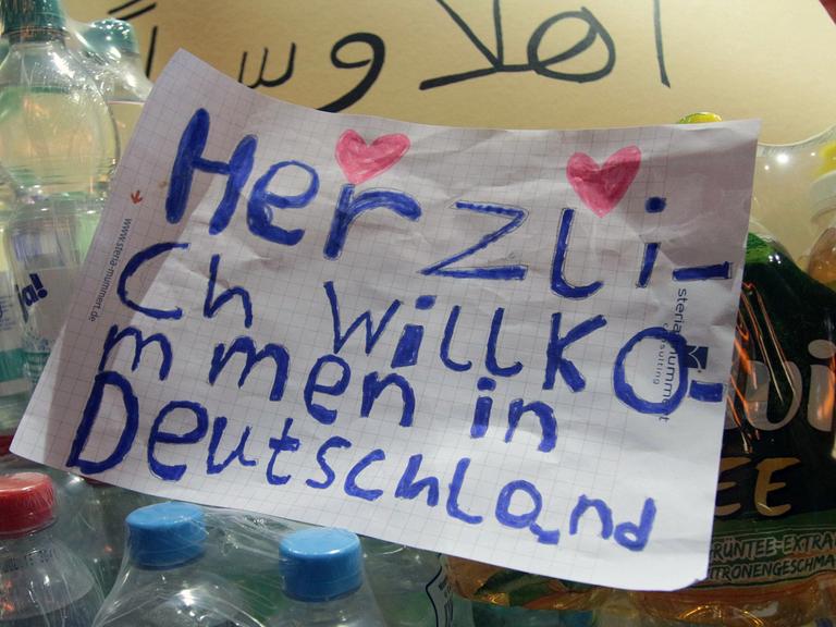 "Herzlich Willkommen in Deutschland" steht mit zwei Herzchen in Kinderschrift auf einem Zettel zwischen Wasserflaschen