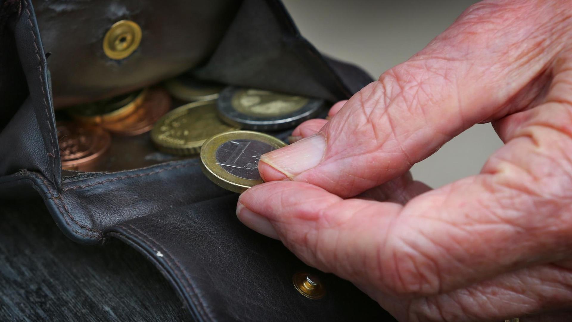 Eine Rentnerin hält am 13.07.2015 in Kempten (Bayern) einen Geldbeutel mit verschiedenen Euromünzen.