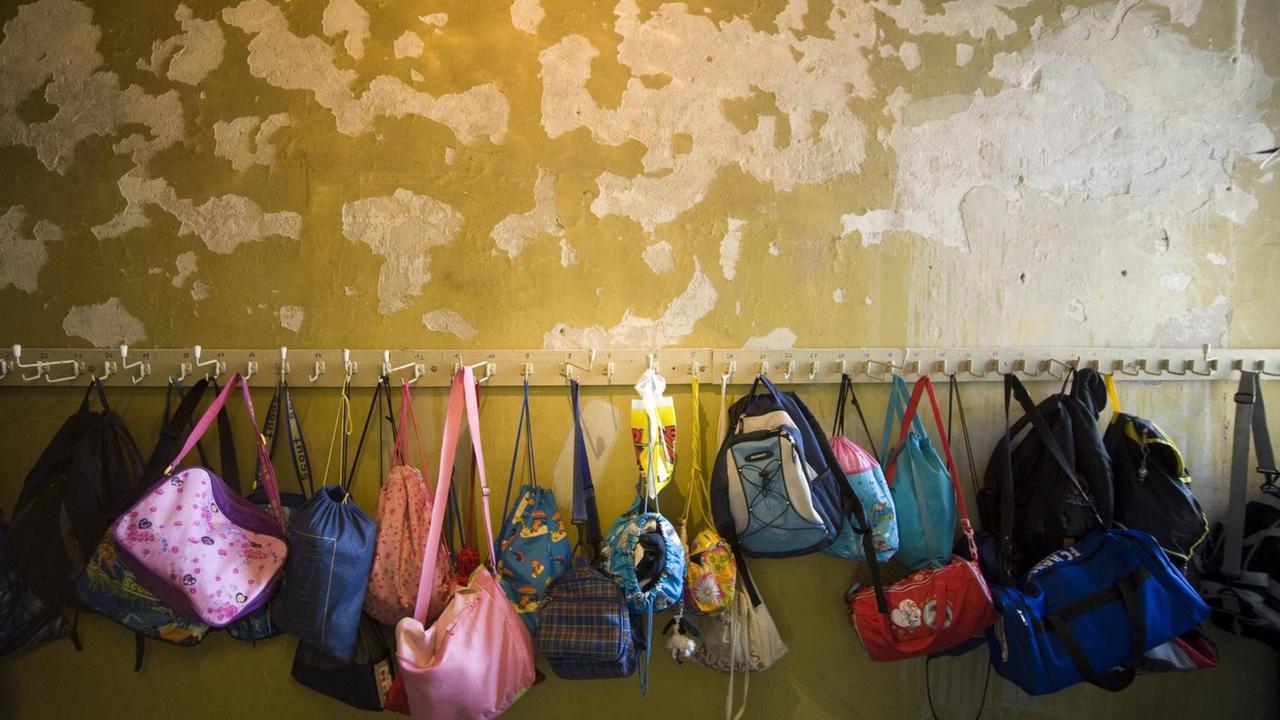 An einer Schulgarderobe hängen Taschen und Rucksäcke von den Kindern. An einer Schulgarderobe hängen Taschen und Rucksäcke von den Kindern.