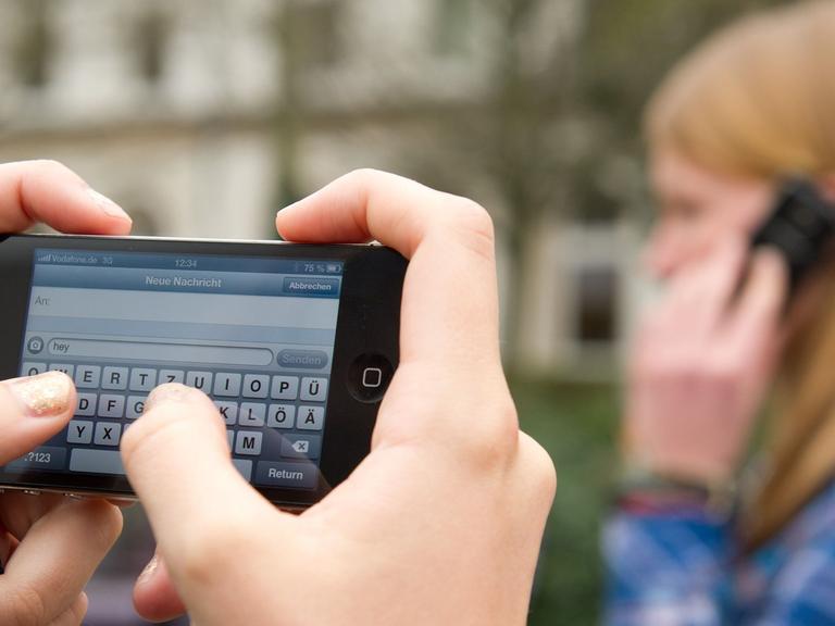 Schüler schreiben SMS und telefonieren am 22.04.2013 auf einem Schulhof in Braunschweig (Niedersachsen).