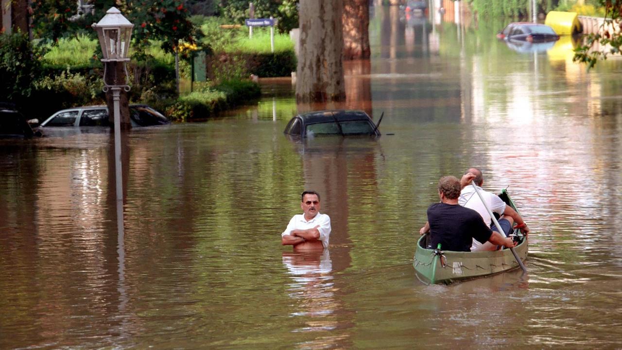 Ein vom Hochwasser betroffener Bewohner steht im Wasser und beobachtet im Überschwemmungsgebiete Dresden-Laubegast ein vorbeifahrendes Ruderboot.