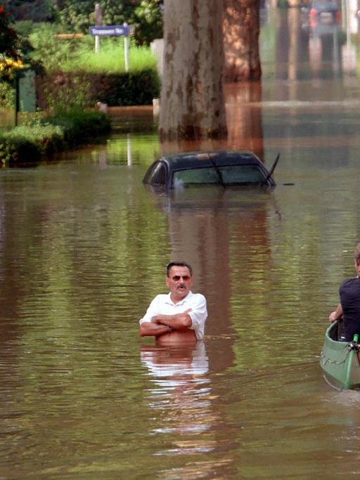 Ein vom Hochwasser betroffener Bewohner steht im Wasser und beobachtet im Überschwemmungsgebiete Dresden-Laubegast ein vorbeifahrendes Ruderboot.