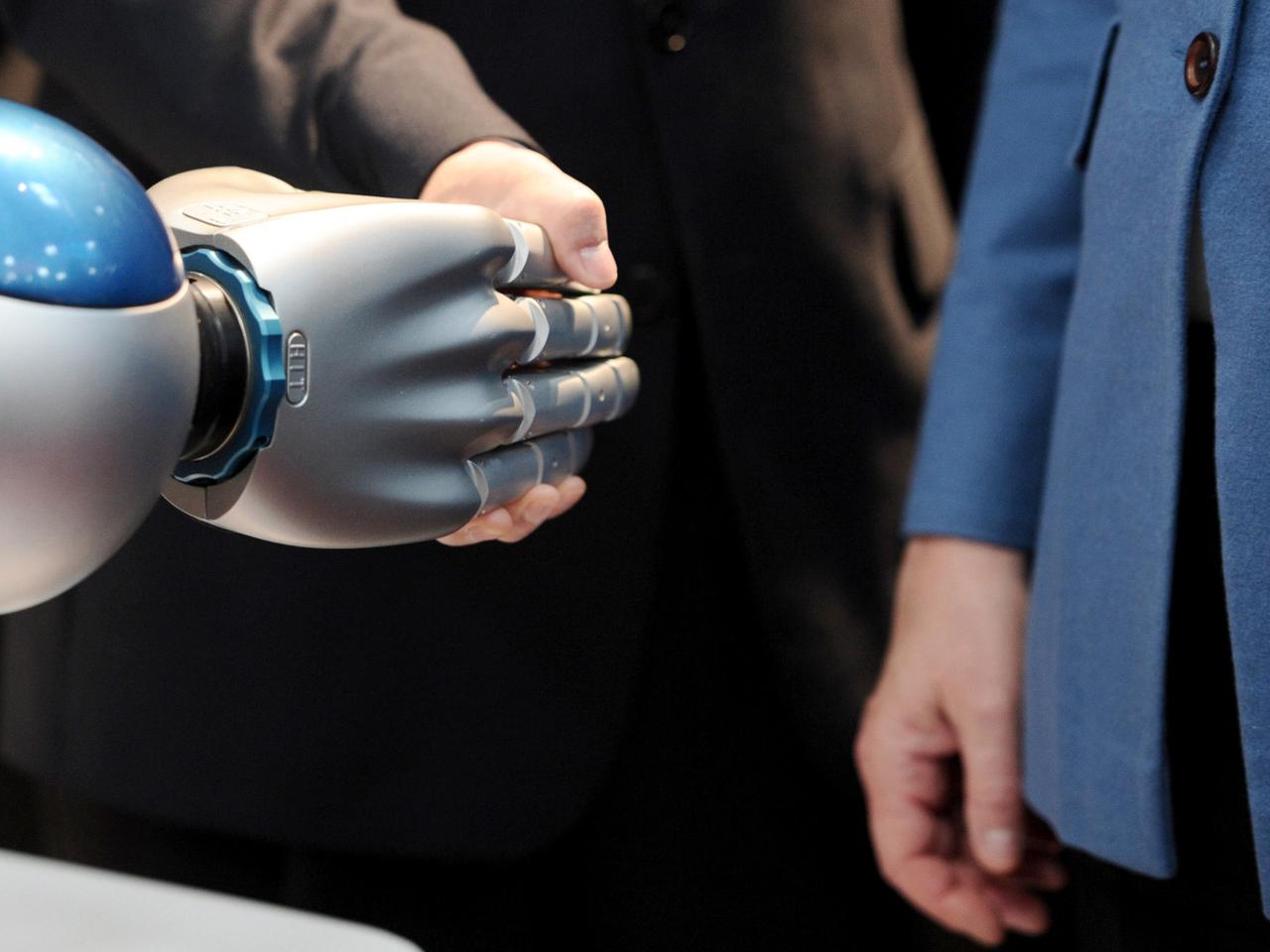 Eine Roboterhand greift eine menschliche 