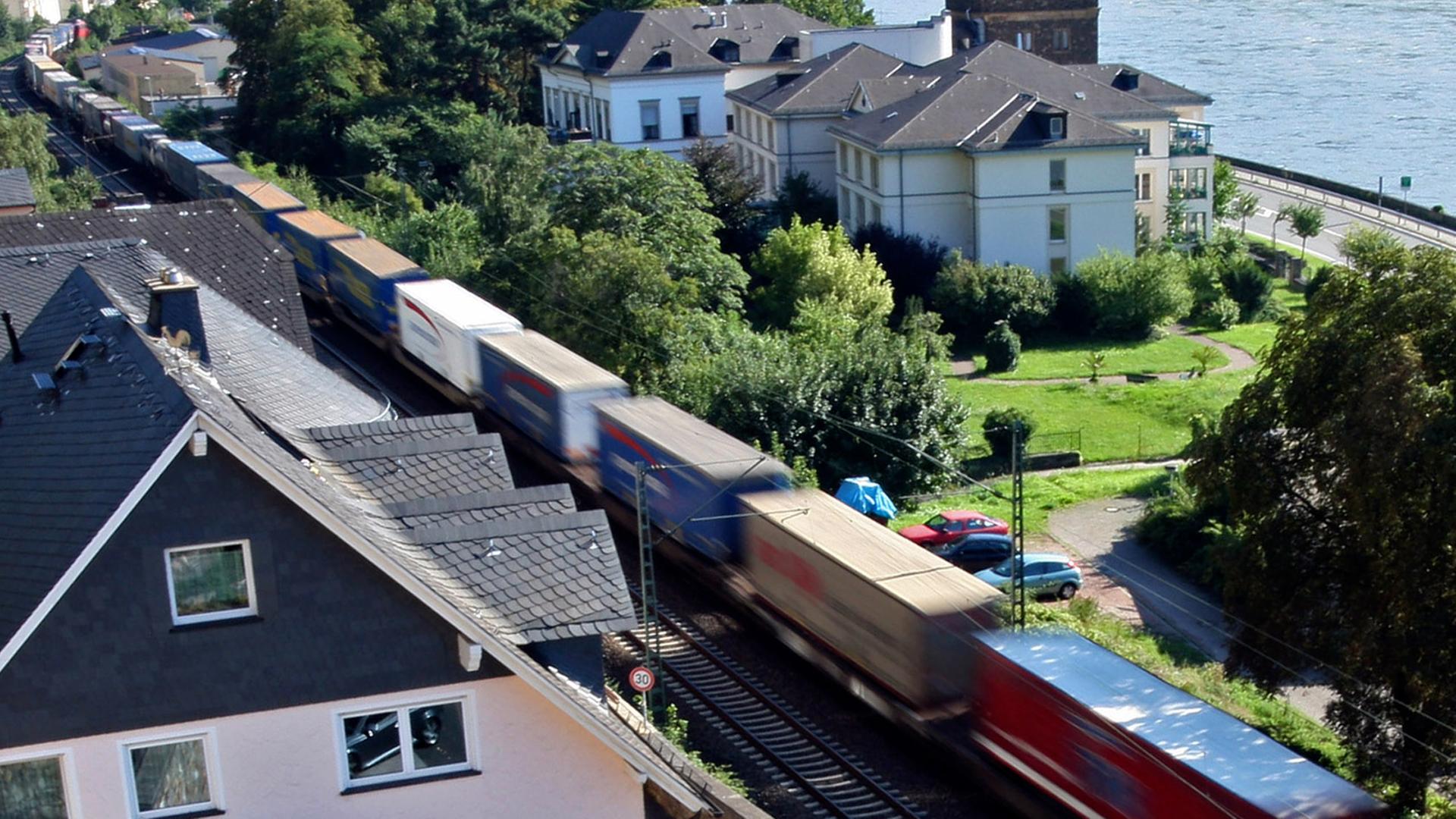 Ein Güterzug fährt an Häusern in Assmanshausen (Rüdesheim) vorbei