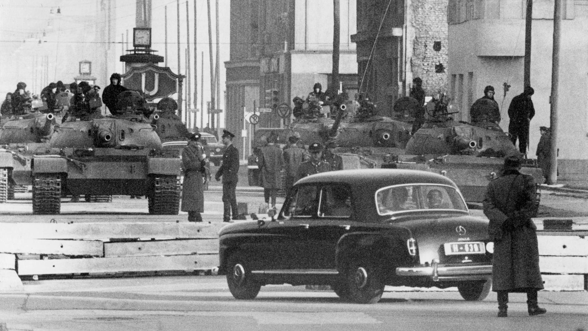 Gespannte Situation wenige Wochen nach dem Mauerbau: Sowjetische Panzer vom TypT54 stehen am 28.10.1961 am Sektorengrenzübergang für Diplomaten und Ausländer in der Friedrichstraße, etwa 150 Meter hinter der Grenzlinie in Ostberlin. Vorn ein Diplomatenwagen kurz vor der Slalomsperre.