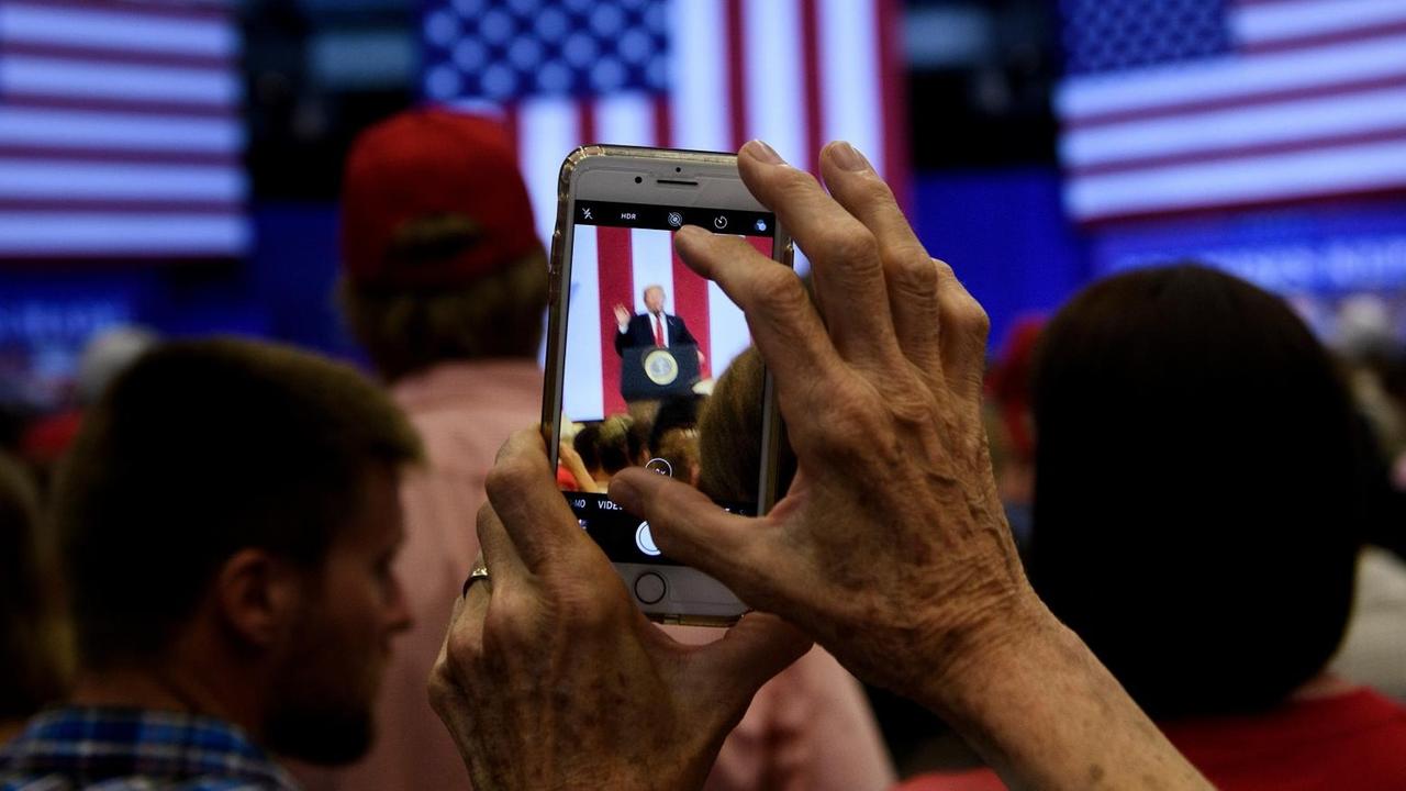 Eine Frau fotografiert Donald Trump bei einer Wahlkampf-Veranstaltung mit ihrem Smartphone. Eine Frau fotografiert Donald Trump bei einer Wahlkampf-Veranstaltung mit ihrem Smartphone.