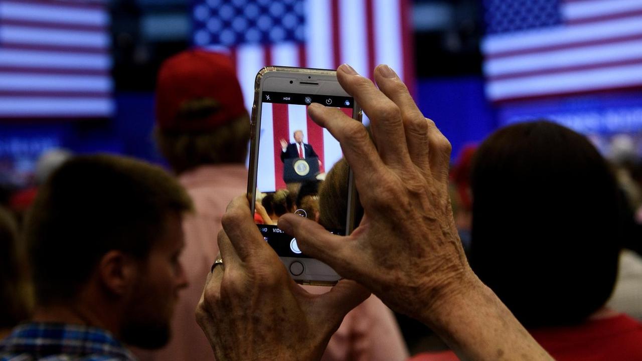 Eine Frau fotografiert Donald Trump bei einer Wahlkampf-Veranstaltung mit ihrem Smartphone. Eine Frau fotografiert Donald Trump bei einer Wahlkampf-Veranstaltung mit ihrem Smartphone.