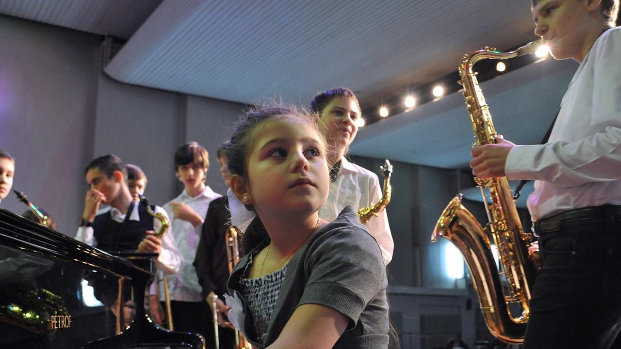 Ein Mädchen am Klavier hört einem Jungen beim Saxofon-Spielen zu. Ein Mädchen am Klavier hört einem Jungen beim Saxofon-Spielen zu.
