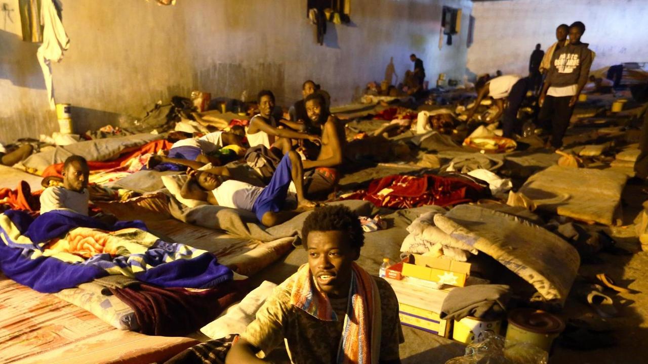 Afrikanische Geflüchtete in einem Lager in Tripolis in Libyen. Sie liegen auf dem Boden auf Matten. Keine Fenster, dicht an dicht. Afrikanische Geflüchtete in einem Lager in Tripolis in Libyen. Sie liegen auf dem Boden auf Matten. Keine Fenster, dicht an dicht.