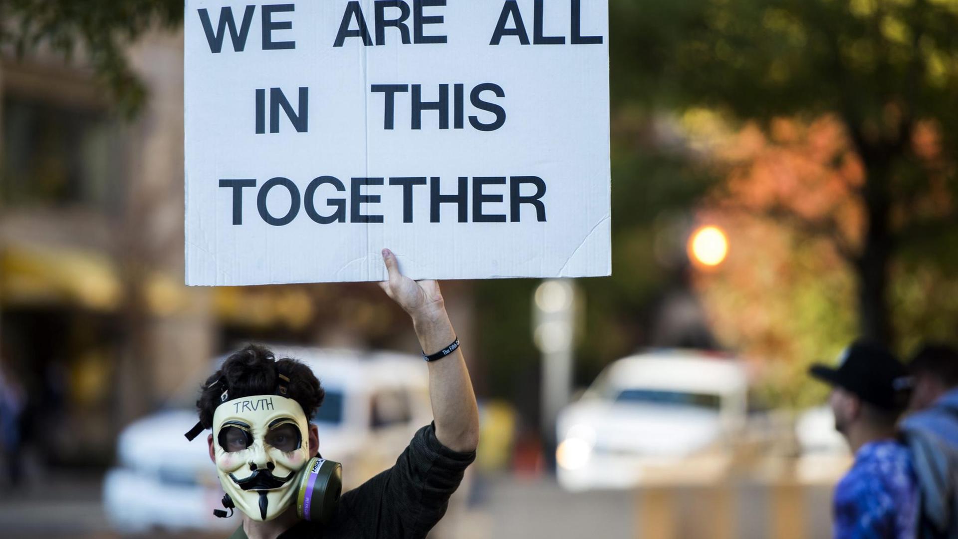 Ein Protestant mit einer Maske, die von Aktivisten der 'Anonymous'-Gruppe verwendet wird Ein Protestant mit einer Maske, die von Aktivisten der 'Anonymous'-Gruppe verwendet wird