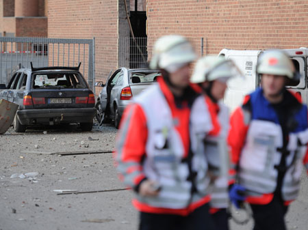 Nach der Explosion einer Weltkriegsbombe gehen Rettungskräfte an zerstörten Autos in Euskirchen vorbei.
