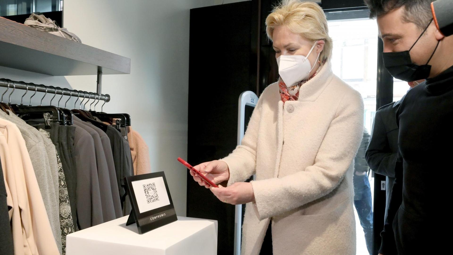Bei einem Presstermin in einem Modegeschäft scannt Manuela Schwesig mit einem Smartphone einen QR-Code auf einem Aufsteller ein - sie demonstriert so, wie die Luca-App funktioniert.