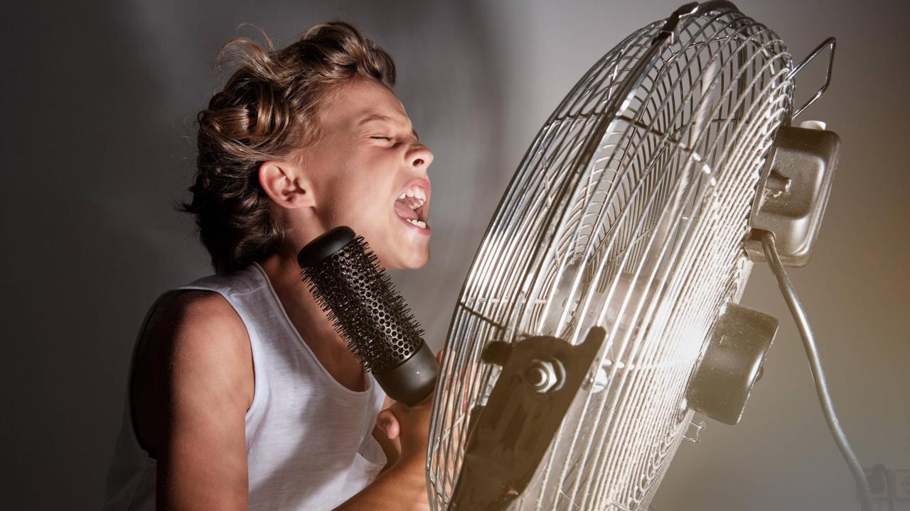 Ein Junge singt vor einem Ventilator in ein Haarbürsten-Mikrofon Ein Junge singt vor einem Ventilator in ein Haarbürsten-Mikrofon