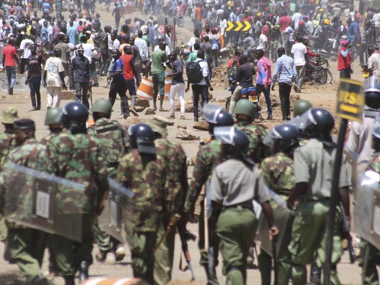 Polizisten einer Spezialeinheit treffen am 02.10.2017 in Kisumu (Kenia) auf eine Gruppe von Demonstranten. Im Streit um eine neue Präsidentschaftswahl in Kenia hat die Polizei teils Tränengas gegen Demonstranten eingesetzt. Hunderte Unterstützer der Opposition folgten am Montag dem Aufruf des Oppositionsführers Odinga und gingen in Kenias Hauptstadt Nairobi sowie in anderen Städten auf die Straße.