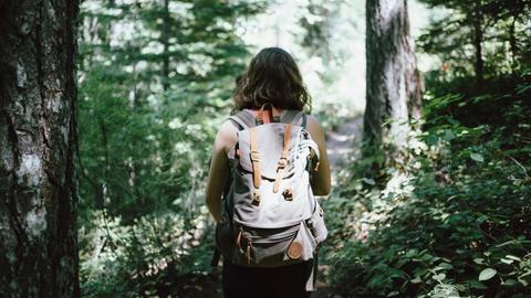 Eine Frau mit Rucksack wandert in einem Wald.